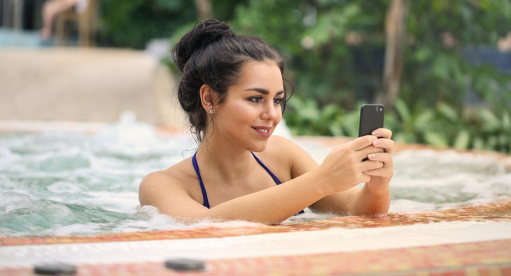 Se for usar o celular na piscina, é melhor segurar ele firme, como essa moça. Foto: Pexels.
